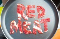 The inscription RED MEAT on the teflon frying pan lined with pieces of raw meat