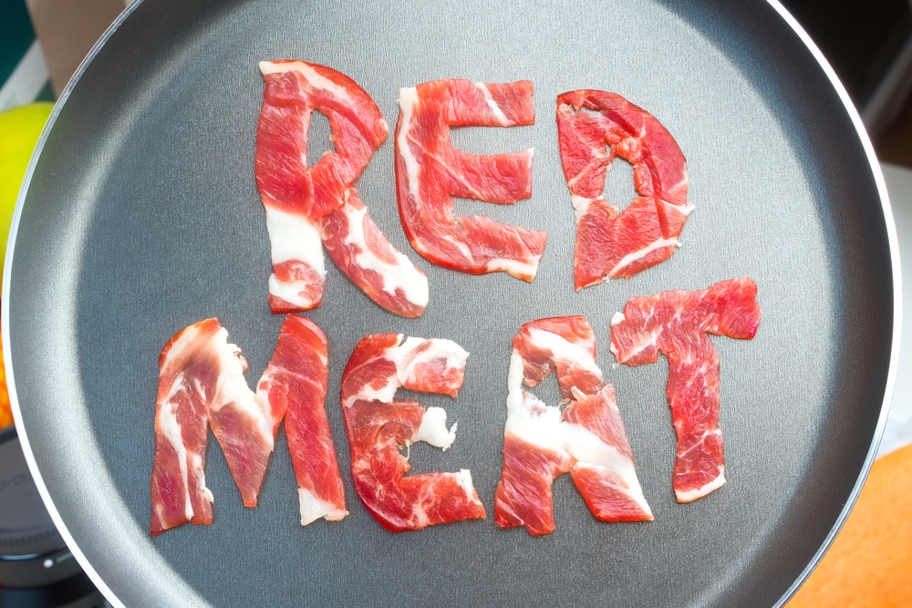 The inscription RED MEAT on the teflon frying pan lined with pieces of raw meat