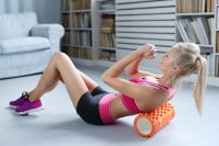 A woman working on her sore back and shoulders by foam rolling