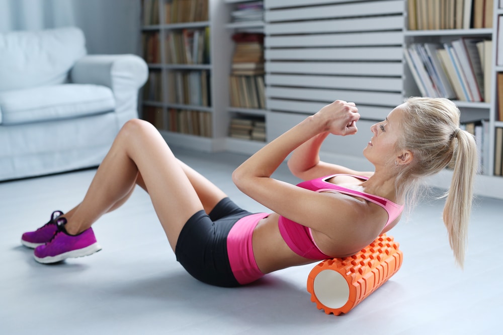 A woman working on her sore back and shoulders by foam rolling