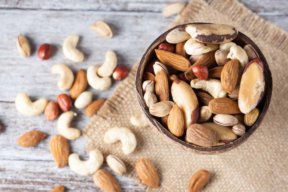 image of healthy nuts in a bowl and on a table. Eating Nuts are a healthy snack alternative