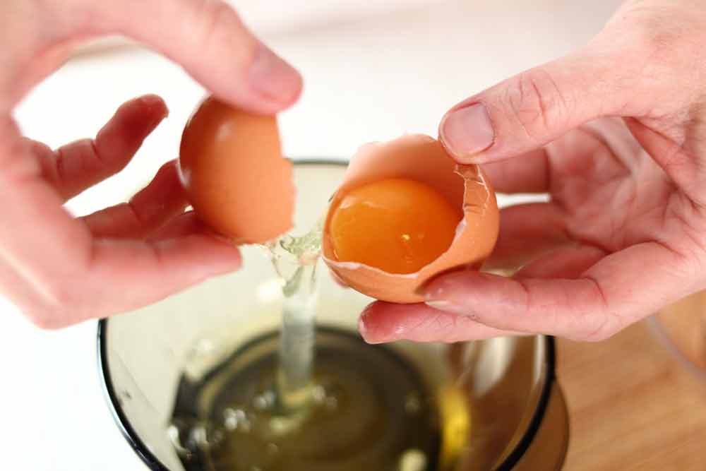 image of a person separating the yolk from an egg to make egg whites