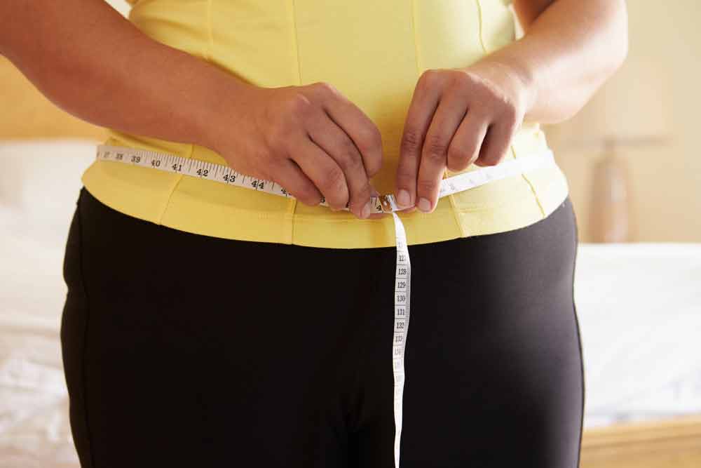 image of over weight female measuring her waist