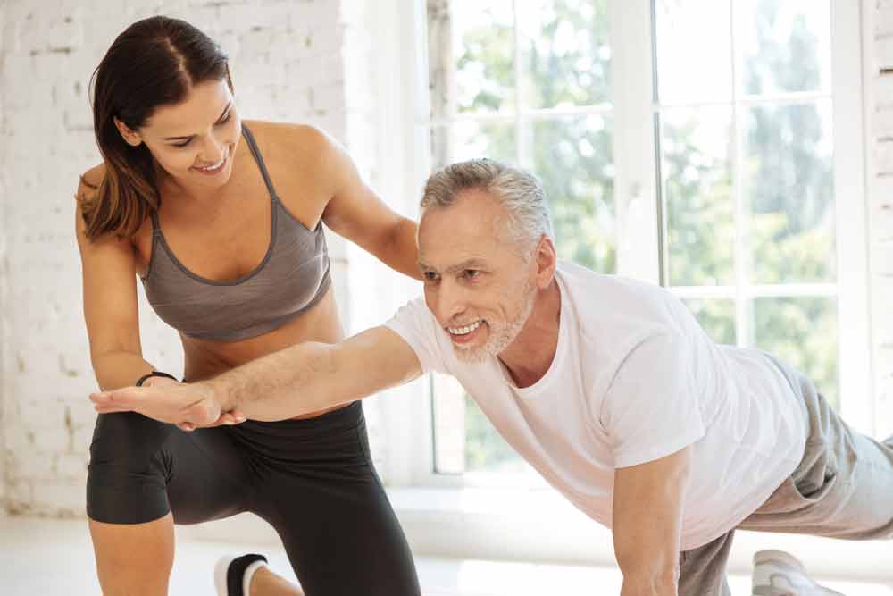 image of young female trainer supervising a senior male exerciser helping to prevent loss of muscle