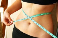image of woman's waist with a measuring tape around it making sure she doesn't have weight regain