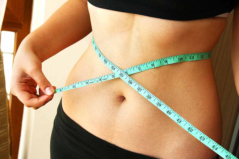 image of woman's waist with a measuring tape around it checking to see if she has had any weight regain