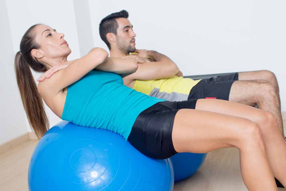 image of a woman and a man doing abdominal crunches on a blue stability ball