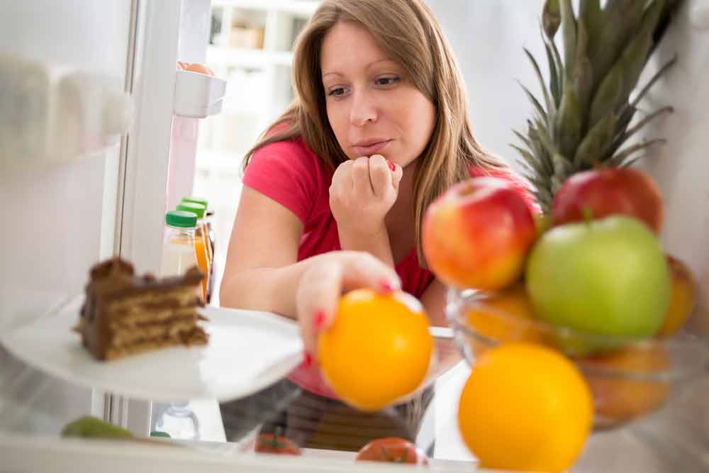 image of a woman trying to decide between eating something good or bad as she works on changing her eating habits