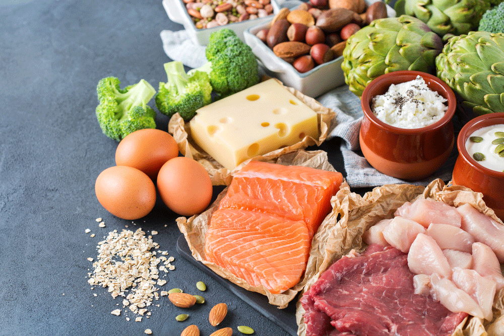 image of assortment of healthy protein sources that you can use to improve the protein content of your diet. Meat beef salmon chicken breast eggs dairy products cheese yogurt beans artichokes broccoli nuts oat meal.