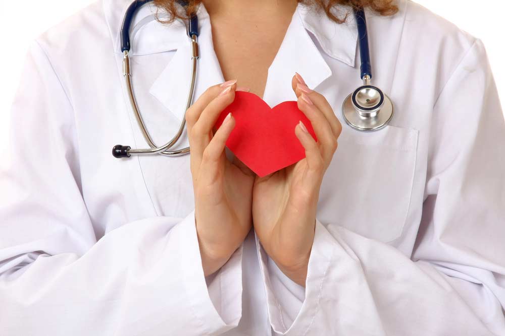 image of a woman doctor holding a red heart to bring attention to heart disease