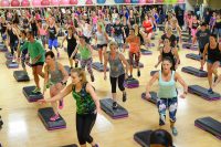 image of a large group of people of various ages working out doing a step aerobics class in a gym