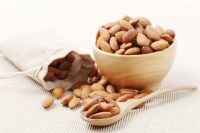 image of dry of almonds nuts in a wooden spoon over corrugated paper background