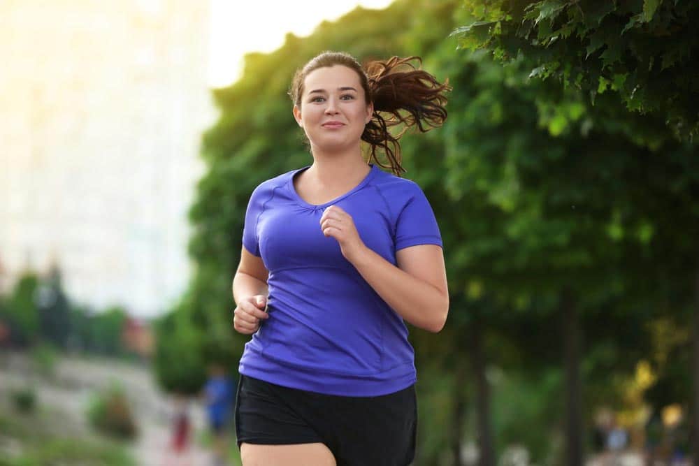 image of overweight young woman jogging in the street. Is being fit more important than body weight as far as health goes?