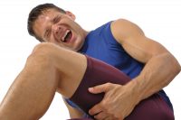 image of a male athlete clutching his hamstring in excruciating pain on white background