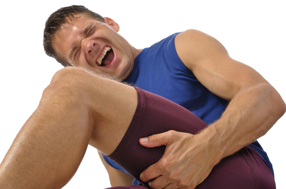 image of a male athlete clutching his hamstring in excruciating pain on white background