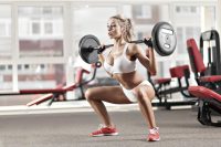 image of woman doing squatting with a barbell at the gym