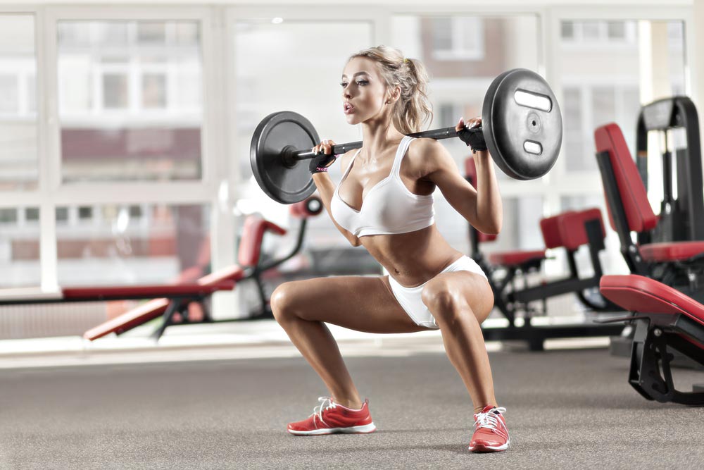 image of woman doing squats with a barbell at the gym