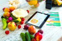 image of organic food and a Tablet PC showing information about healthy nutrition and phytochemical composition.