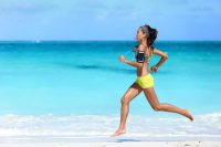 image of female exercising in the heat running barefoot with determination under summer sun in hot weather.