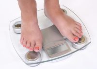 A pair of female feet standing on scale determining her body weight which could impact her risk of getting type 2 diabetes.