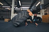 Fit female athlete working out with a huge tire, turning and flipping in the gym. Can extrem exertion cause rhabdomyolysis?