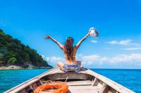 Happy woman traveler in bikini relaxing on boat enjoying her summer vacation