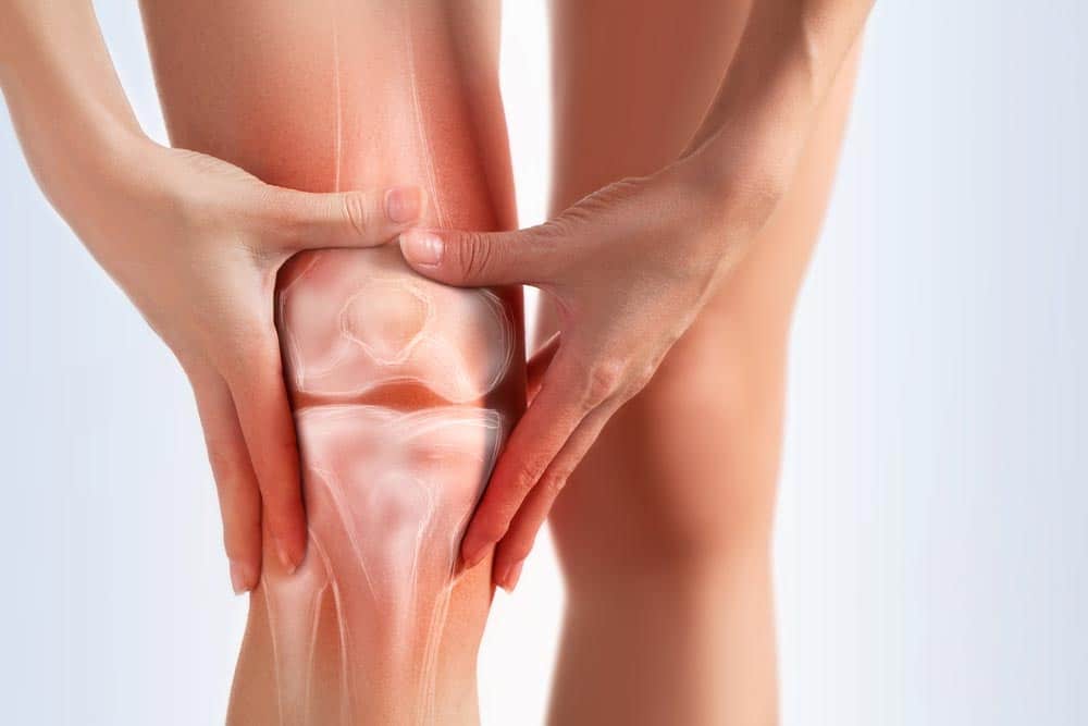 Woman in pain from knee osteoarthritis grabbing her knee 