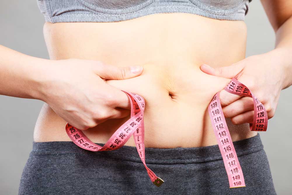 A woman measuring her tummy fat