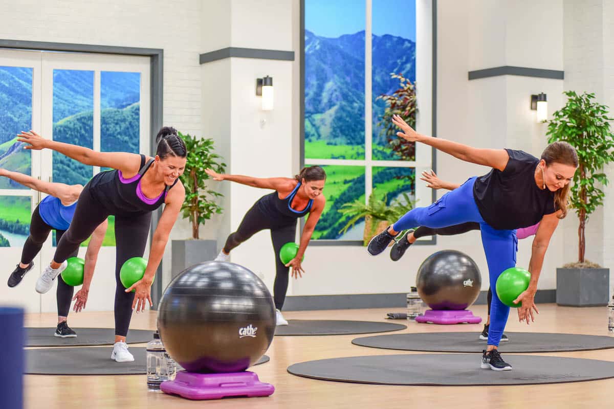 Cathe Friedrich doing a functional training exercise in her Lift, Move & Restore workout program for the active aging exerciser